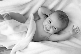 Joyful Baby Smiling Under Soft Blanket
